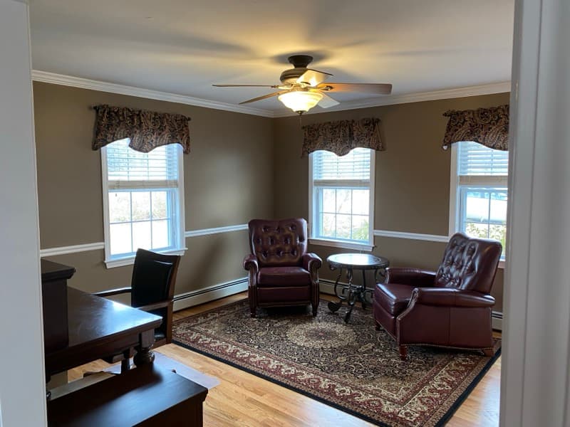 Formal sitting room with warm taupe walls, white crown molding, and chair rail in Haverhill, MA