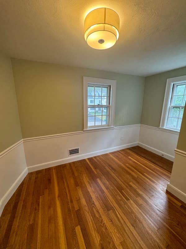 Hallway with sage green walls, white baseboard, and wall sconce in Lynnfield, MA
