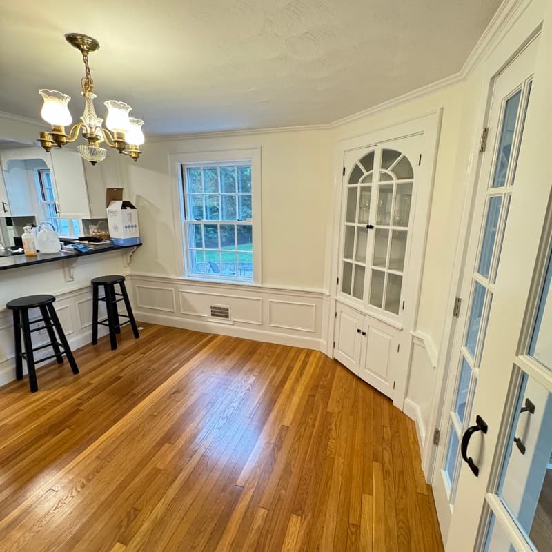 Dining room with cream walls, white wainscoting, and built-in glass-door cabinets in Lynnfield, MA