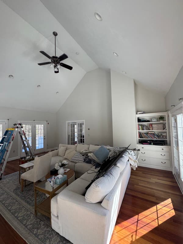 Living room with vaulted ceiling and built-in shelving being painted in Salem, NH