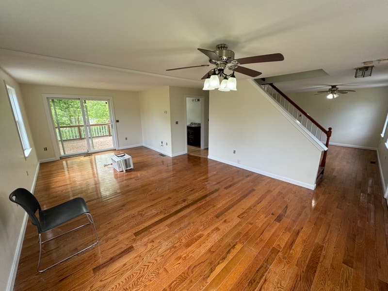 Open-concept living room with off-white walls, hardwood floors, and staircase in Seabrook, NH